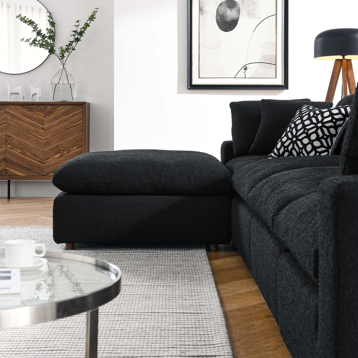 Charcoal fabric sectional sofa with chaise in a modern living room, with patterned pillows and glass coffee table.
