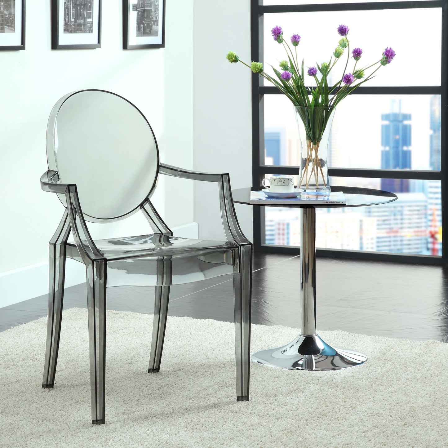 Clear acrylic dining armchairs (set of 2) with rounded backs, beside a glass-topped chrome side table and a vase of purple flowers.