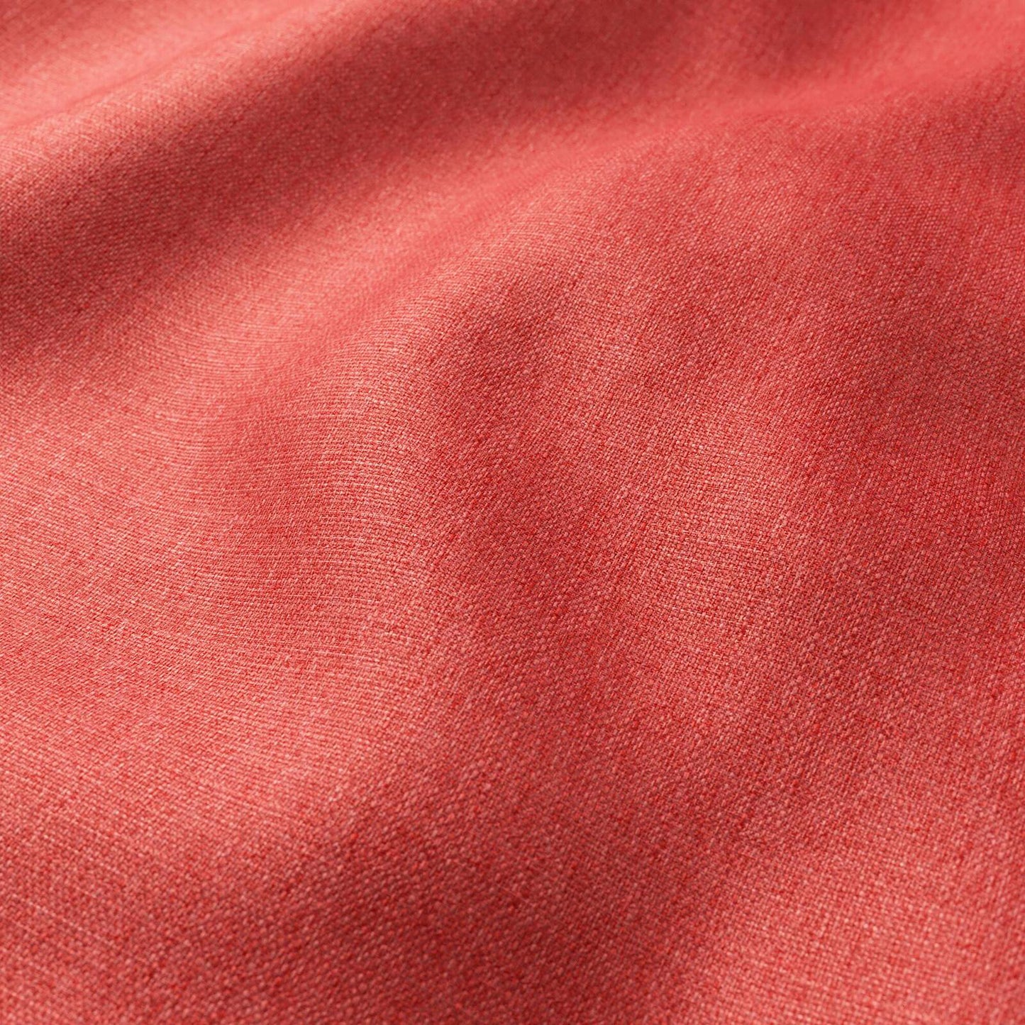 Close-up of coral red woven fabric with soft folds and fine texture.
