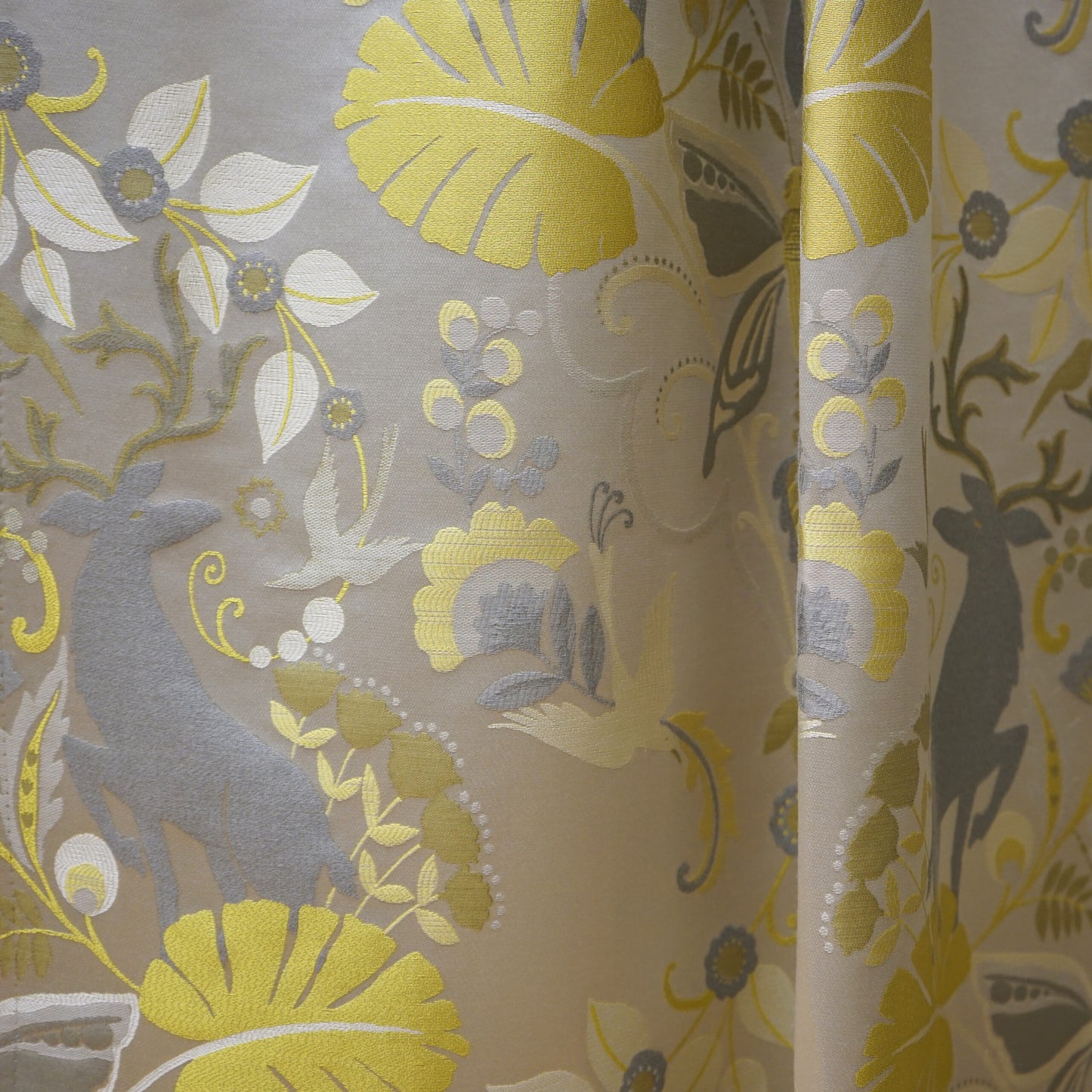 Damask curtain fabric with yellow floral motifs and gray elk silhouettes on beige background