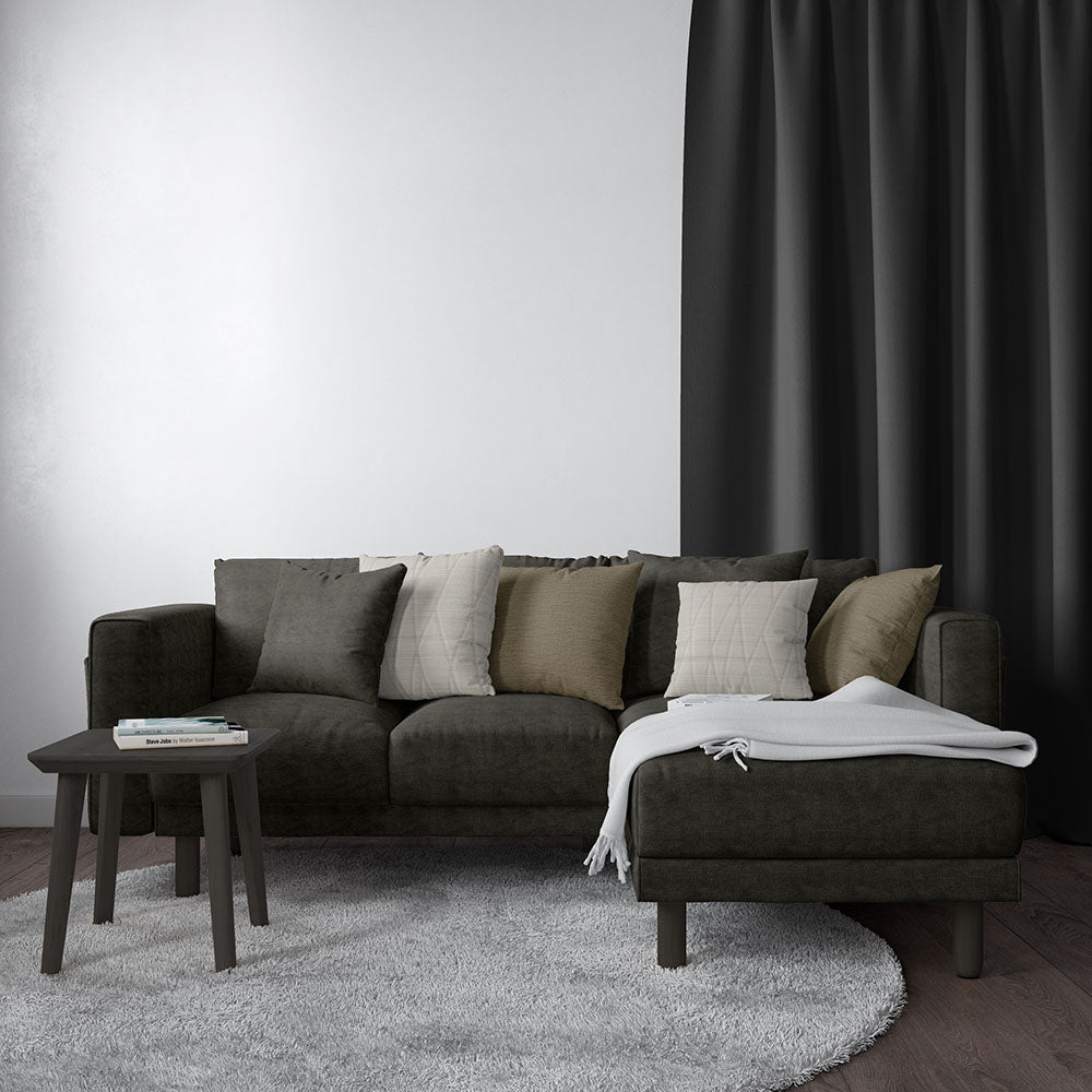 Charcoal L-shaped sectional upholstered in NJ25-984 performance fabric; neutral cushions, white throw on ottoman, round side table, gray rug, black curtains.