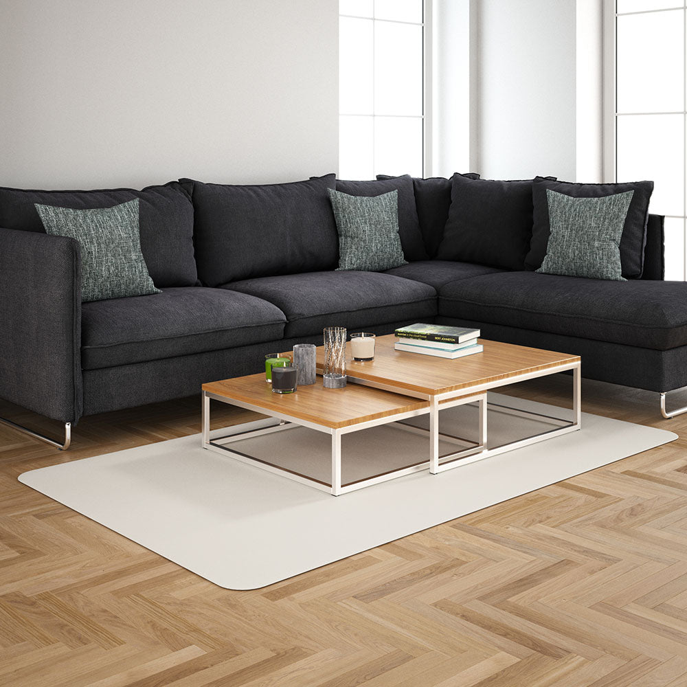 Blue solid-fabric sectional sofa with green cushions, two-tier light wood coffee table on a white metal frame, beige rug, airy living room.