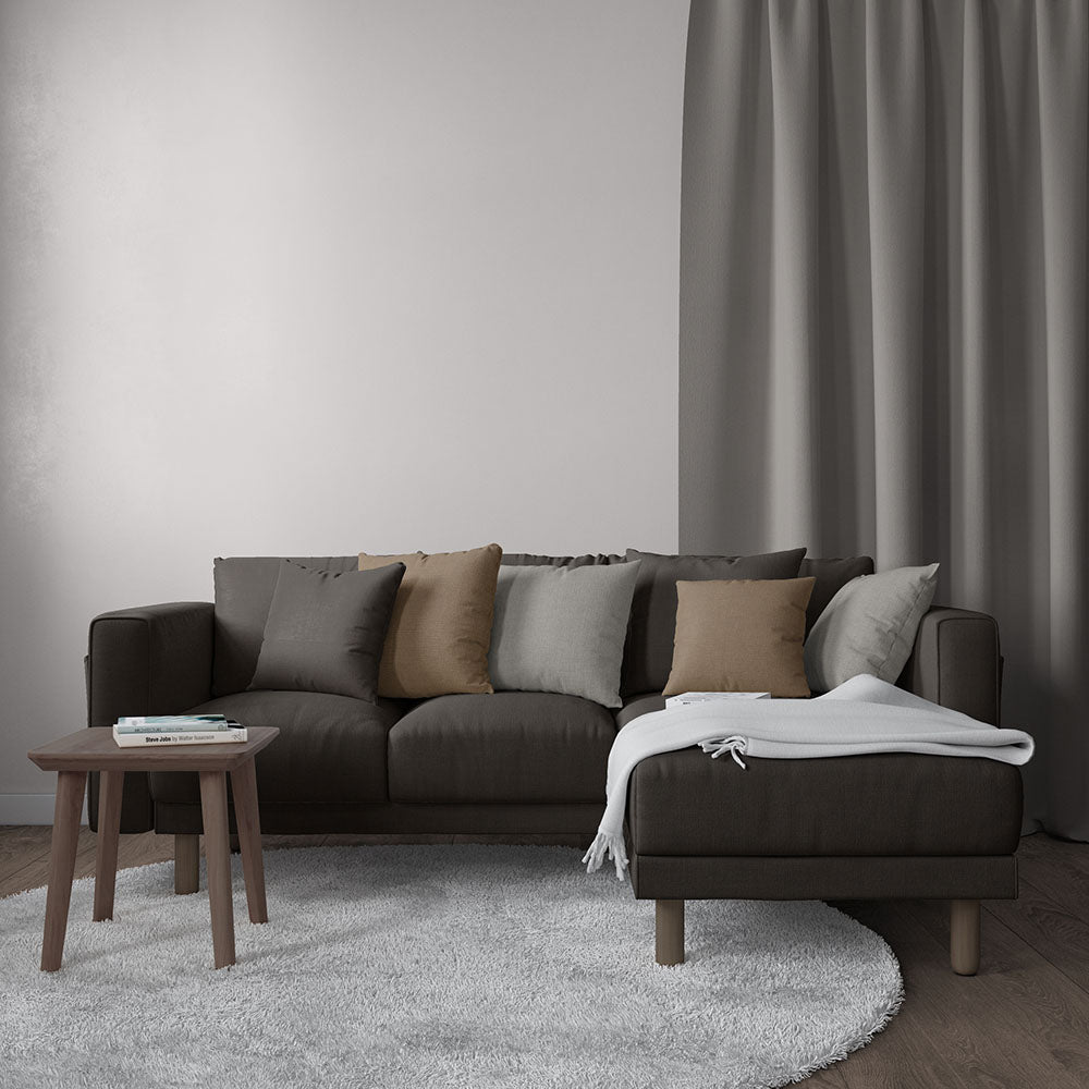 Dark brown sectional sofa with taupe and gray cushions, white throw, round wooden coffee table, light gray rug.