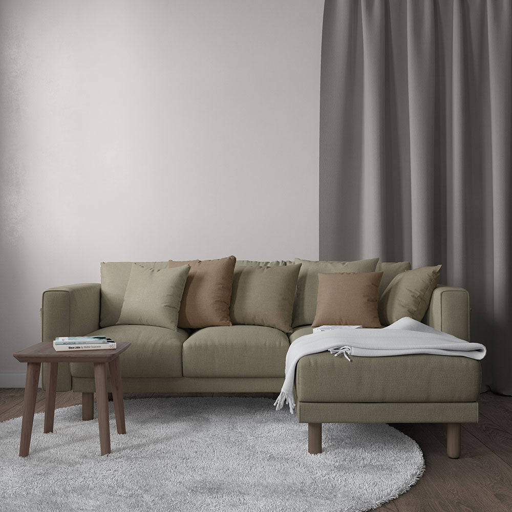 Olive-green fabric sectional sofa with beige cushions and a chaise, a wooden coffee table, and a gray rug in a neutral living room.