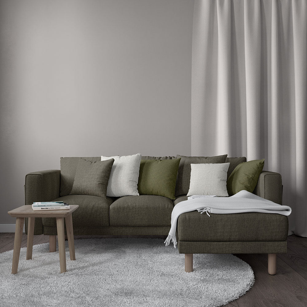Endur Loft modular sofa with chaise in olive-brown, mixed green/gray cushions, wood coffee table, light gray rug and curtains.