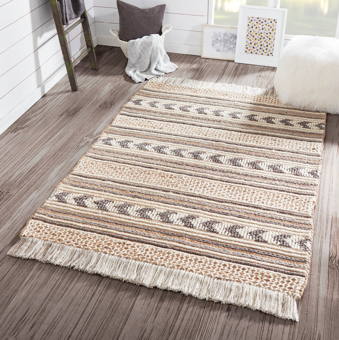 Woven striped area rug with fringed ends in beige, taupe, brown tones on dark wood floor.