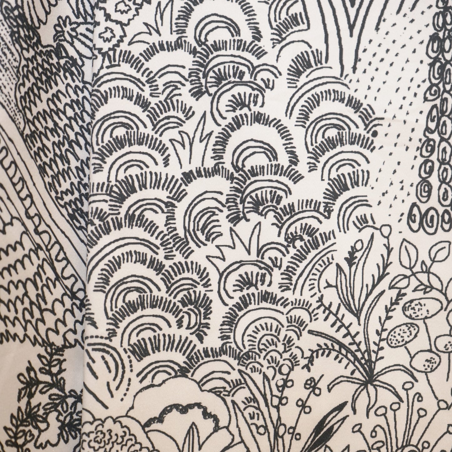 Monochrome etching-style botanical print on fabric featuring trees, leaves and swirling cloud-like arches.