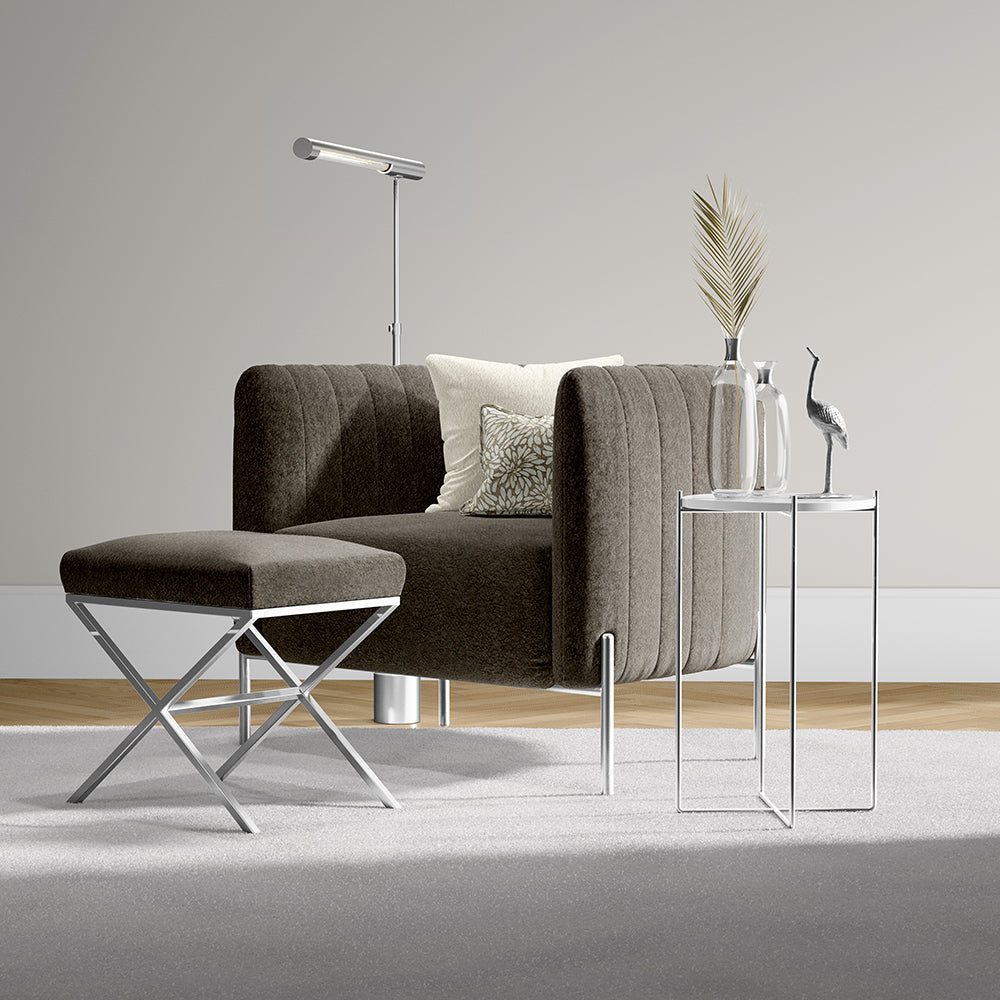 Brown curved fabric sofa with matching ottoman on chrome legs, modern side table with vases and a bird sculpture.