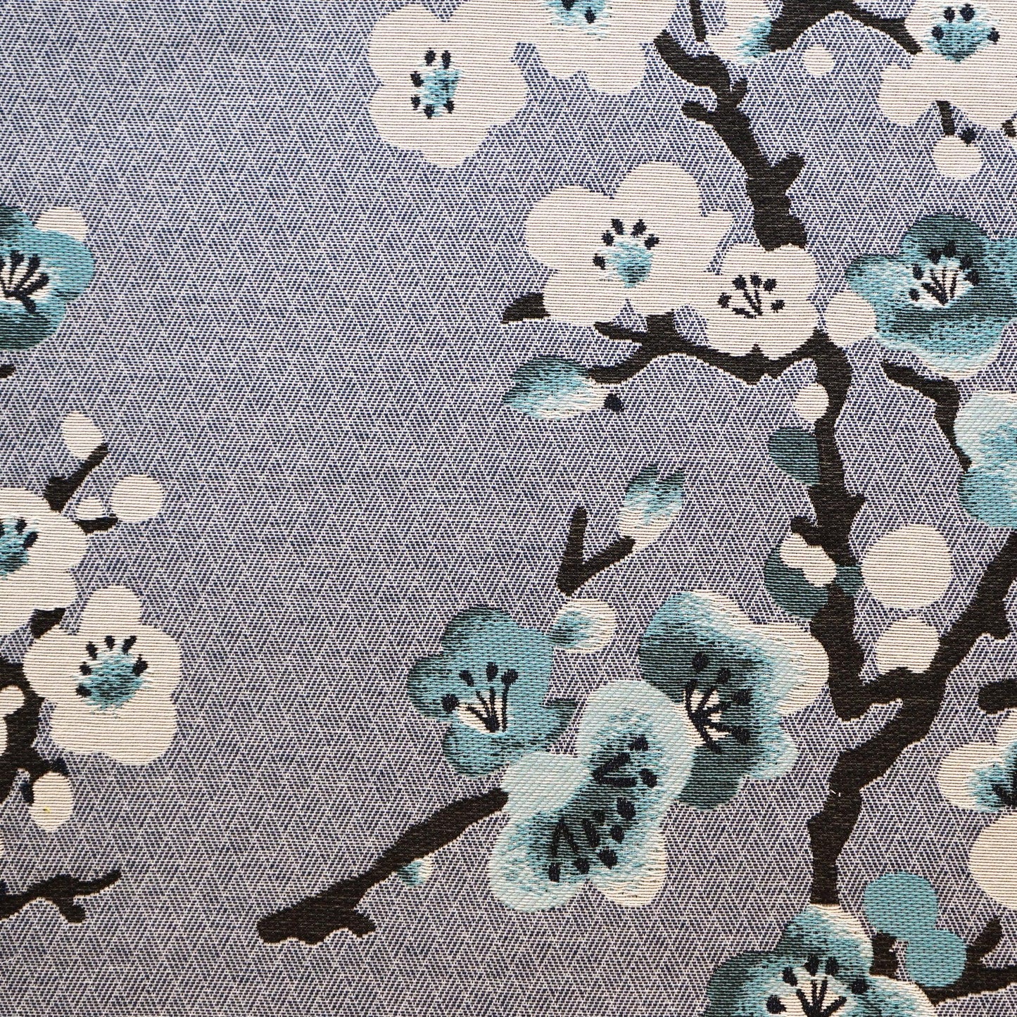 Floral fabric with white and teal blossoms on dark branches against a blue, textured background.