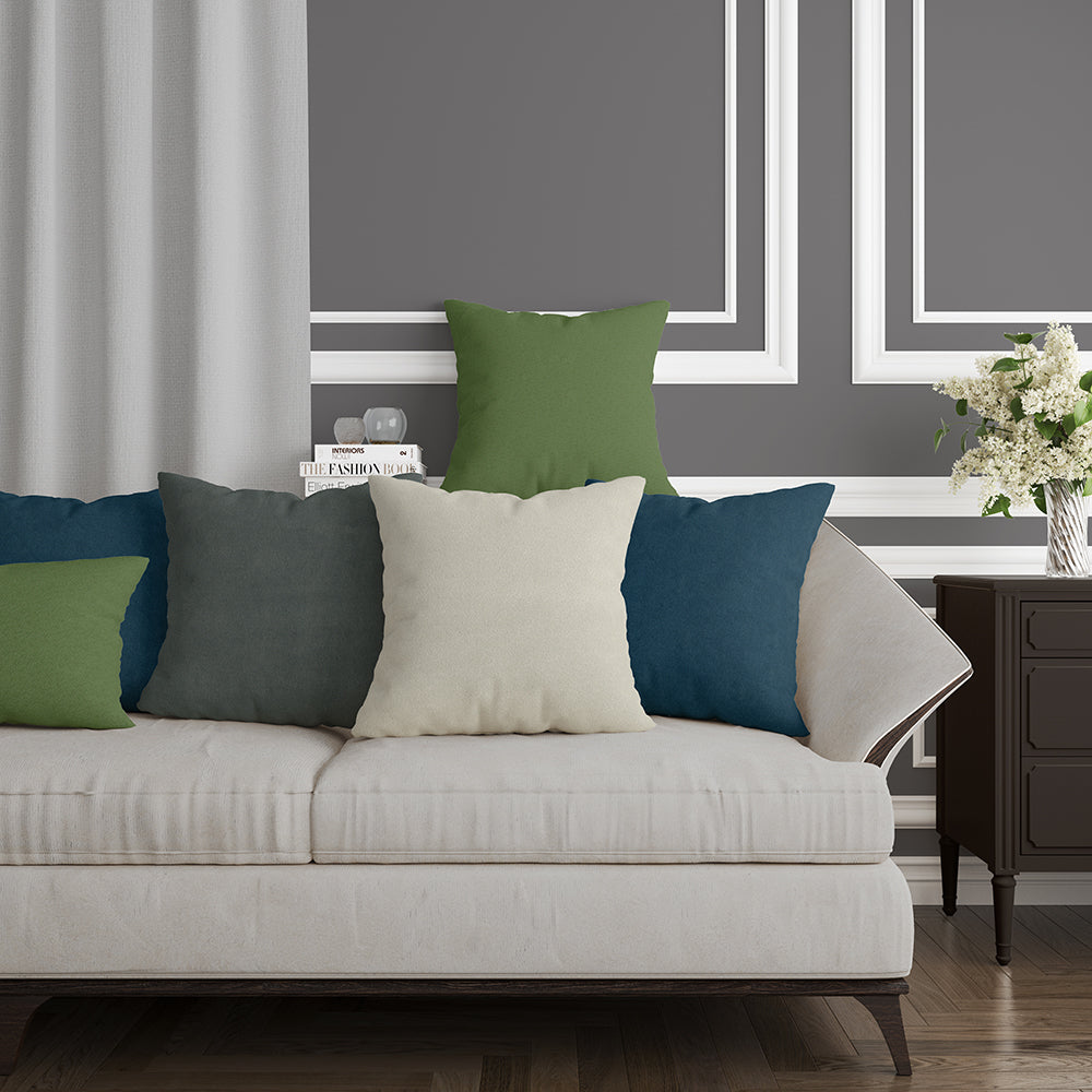 Beige sofa with lime green, olive, cream, teal & navy cushions in a gray paneled living room with a dark wood side table.