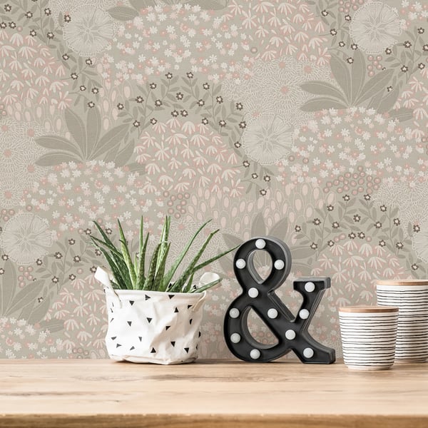 Green succulent in a white geometric pot beside a black marquee ampersand with bulbs, on a wooden table with floral wallpaper.