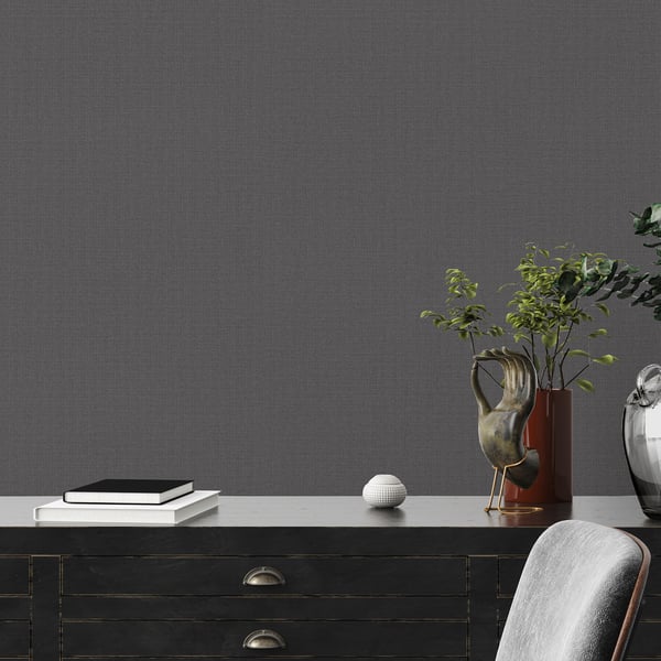 Dark wood sideboard with brass handles, books, white spherical decor, green plants in vases, gray upholstered chair.