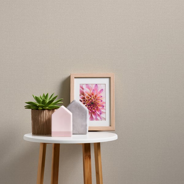 Round white table with wooden legs, green succulent in a ribbed brown pot, pink & gray ceramic houses, framed flower art.