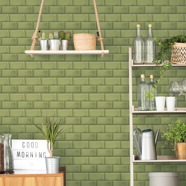 Green metro tile wallcovering on wall with white hanging shelf & shelf unit, glass bottles & potted plants, rustic kitchen decor.