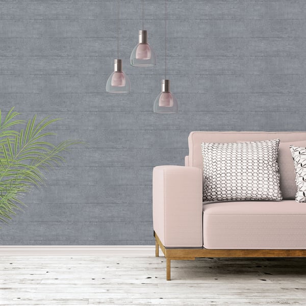Soft pink sofa with wooden legs, patterned cushions, a green plant, pink glass pendant lights, and gray concrete-style wallpaper.