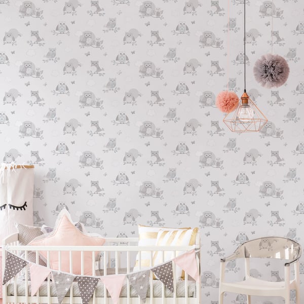 Nursery with gray owl wallpaper, white crib, pink star cushion, pastel bunting, copper pendant light with pink pom-poms