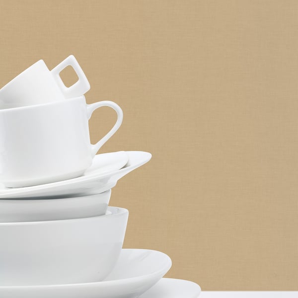 Stack of cream linen wallcovering miniature samples against a beige background.