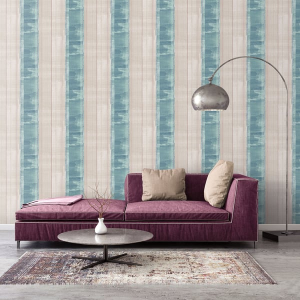 Purple velvet sofa with cream cushions, arched metal floor lamp, round coffee table, teal striped wallpaper and vintage rug.