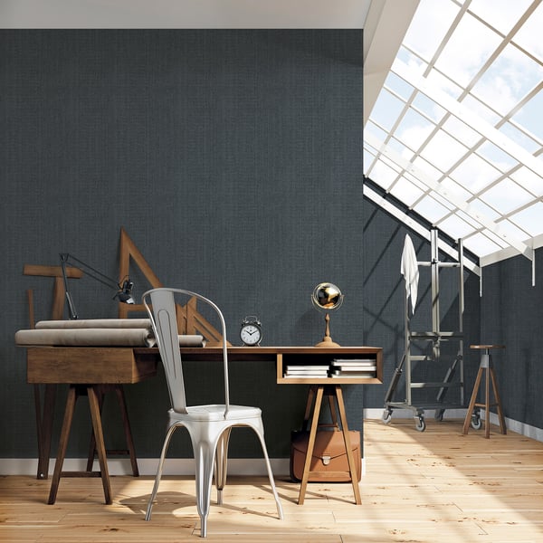 Industrial wooden desk with metal chair in a bright loft studio under skylight, clock and brass lamp on desk.