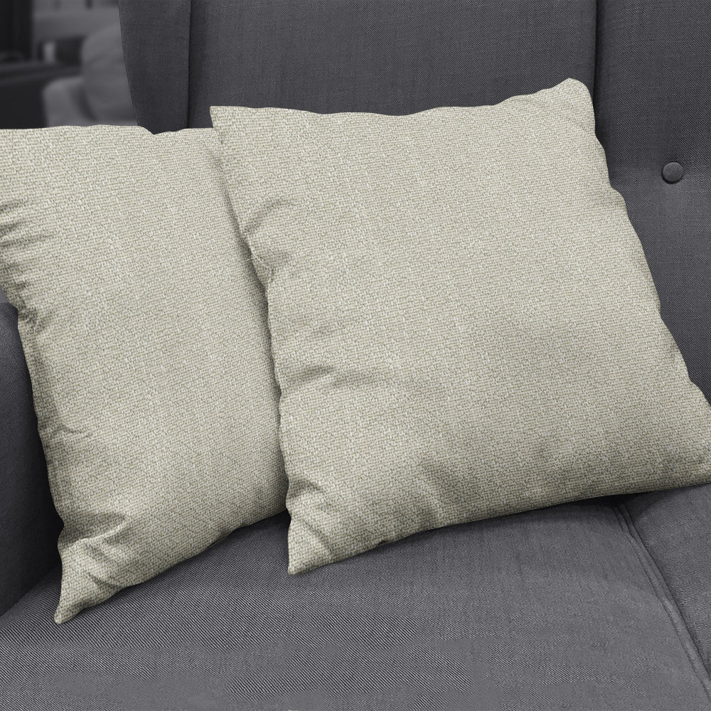 Two beige boucle-textured throw cushions on a dark gray sofa; solid fabric with a soft woven texture.