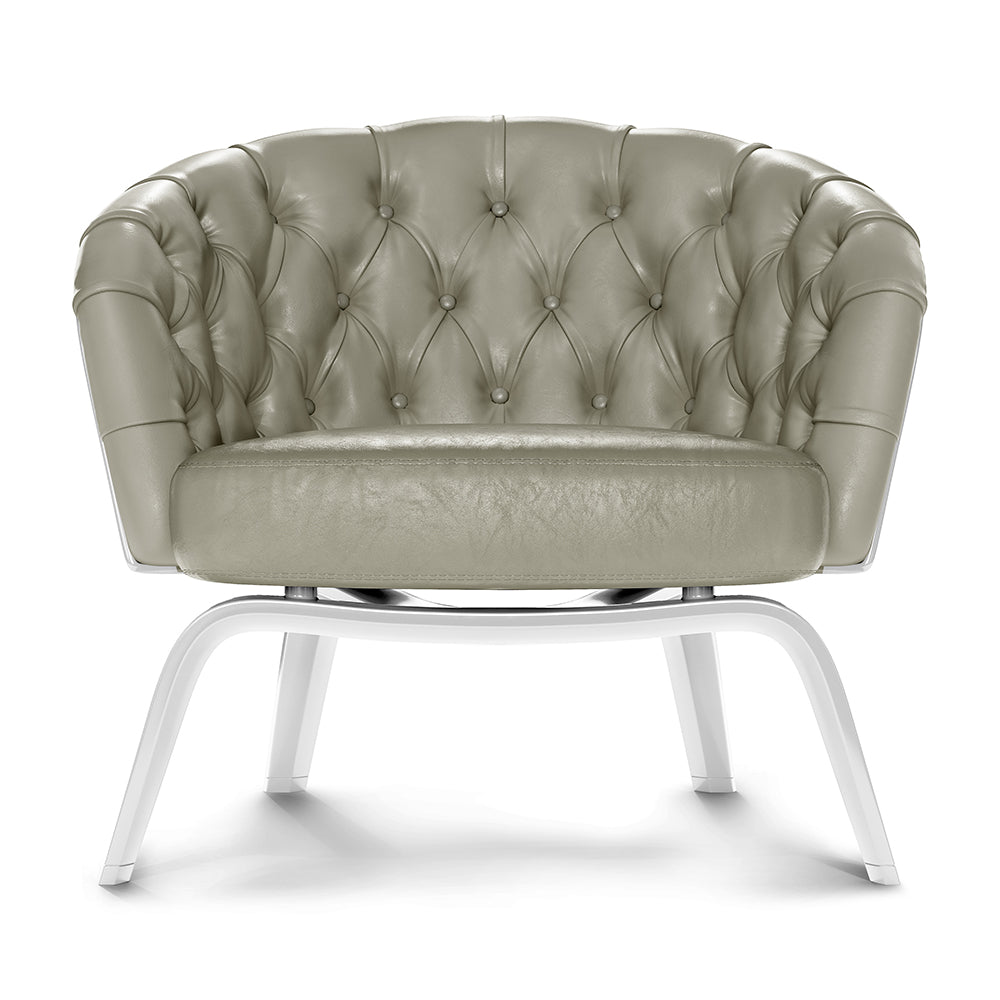 Sage-green tufted leather accent chair with rolled arms and white curved metal legs.