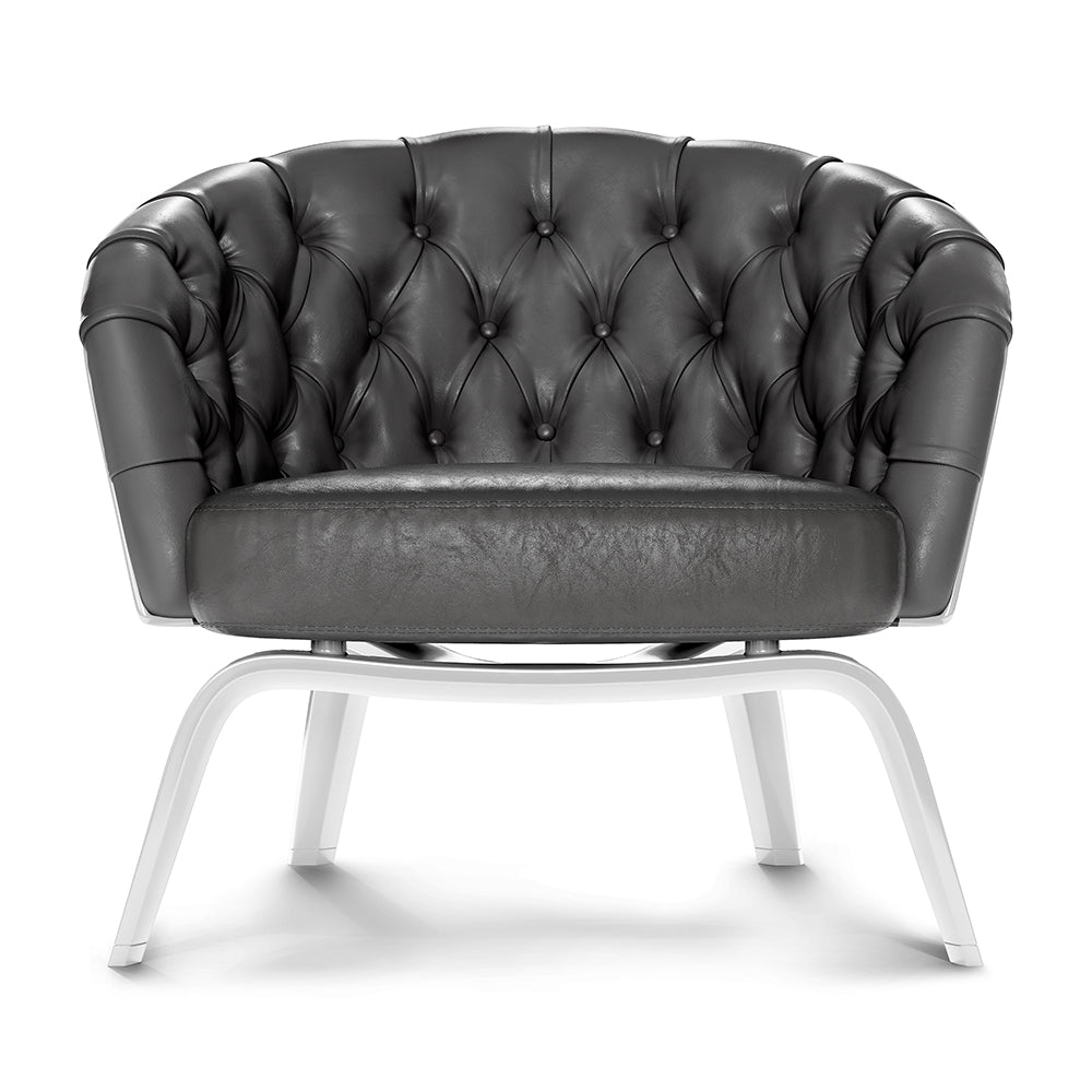 Dark gray, button-tufted leather lounge chair with rounded arms and white metal legs.