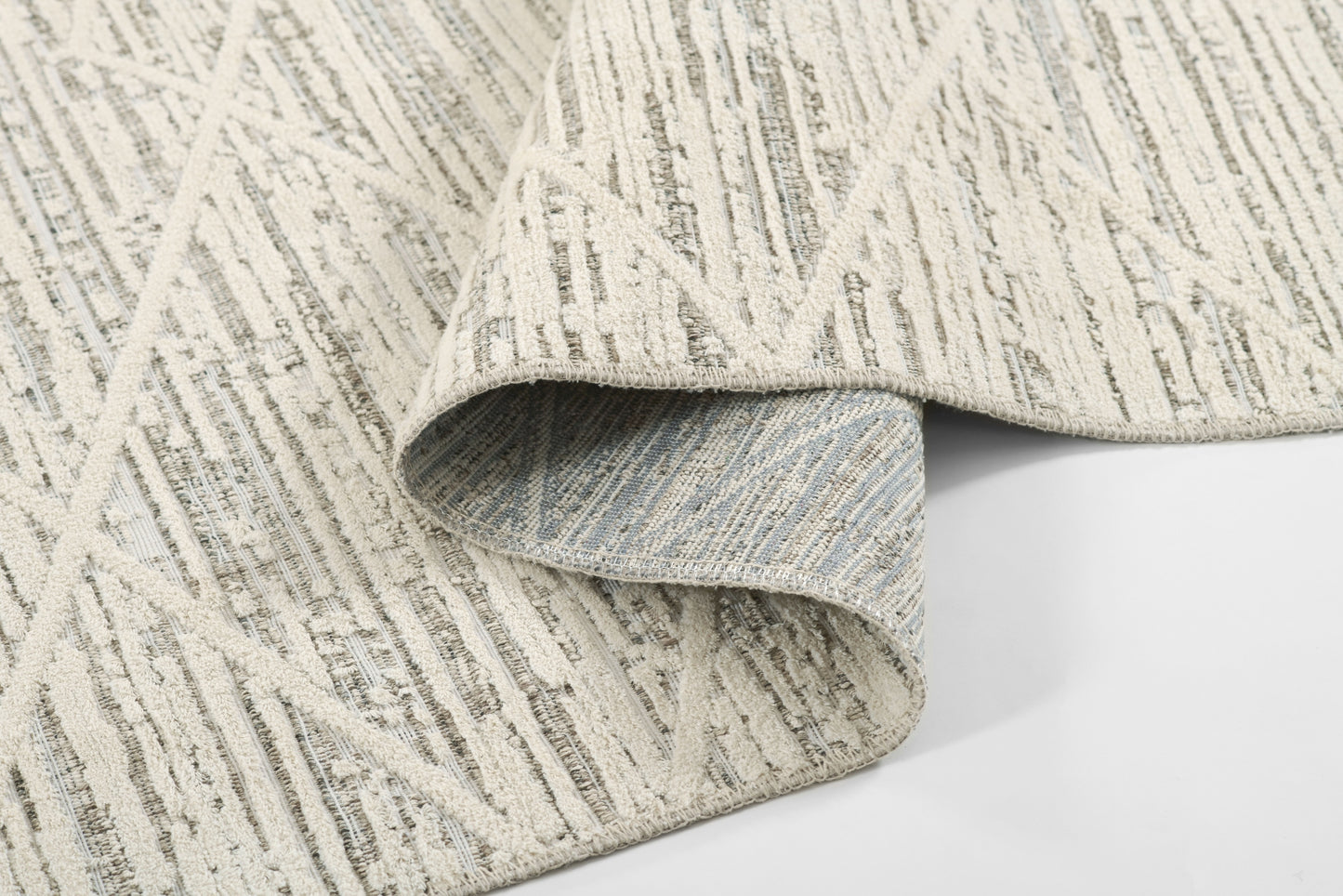 Beige woven area rug with gray linear pattern and soft textured pile, folded edge visible.