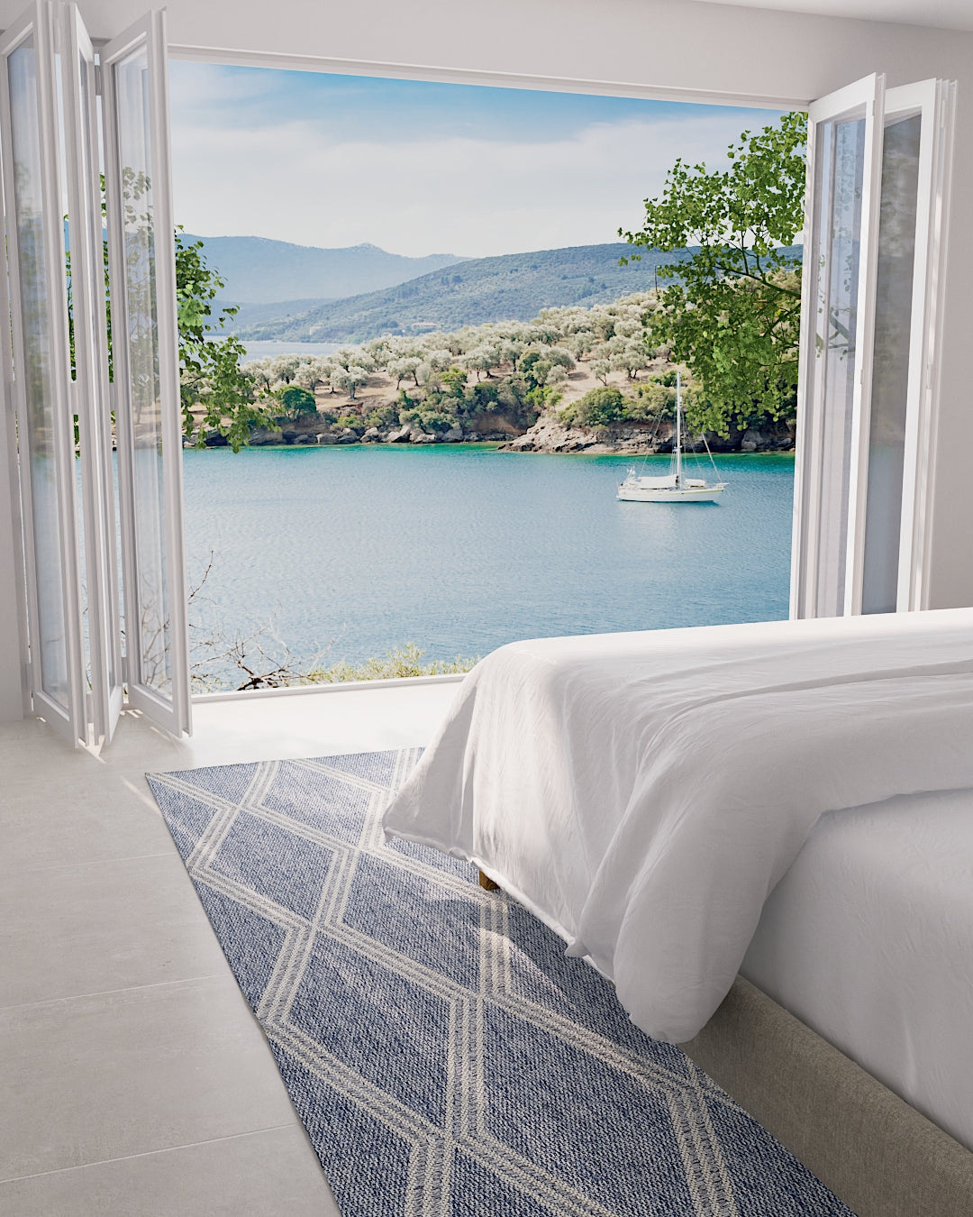 Sunlit bedroom with wide open folding doors to a blue bay, white bedding, and a blue geometric rug.