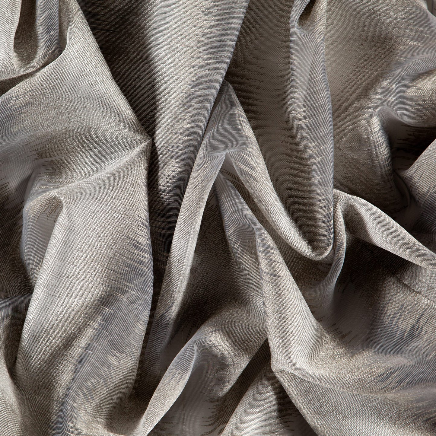 Silver-gray sheer fabric with metallic sheen and dramatic folds; luxurious drape for apparel or home decor.