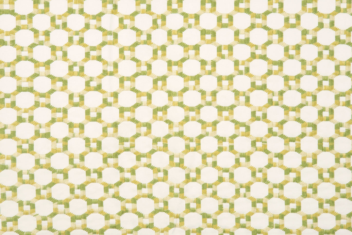 Geometric lattice pattern in white with pale green and gold-yellow interlocking shapes on green fabric.