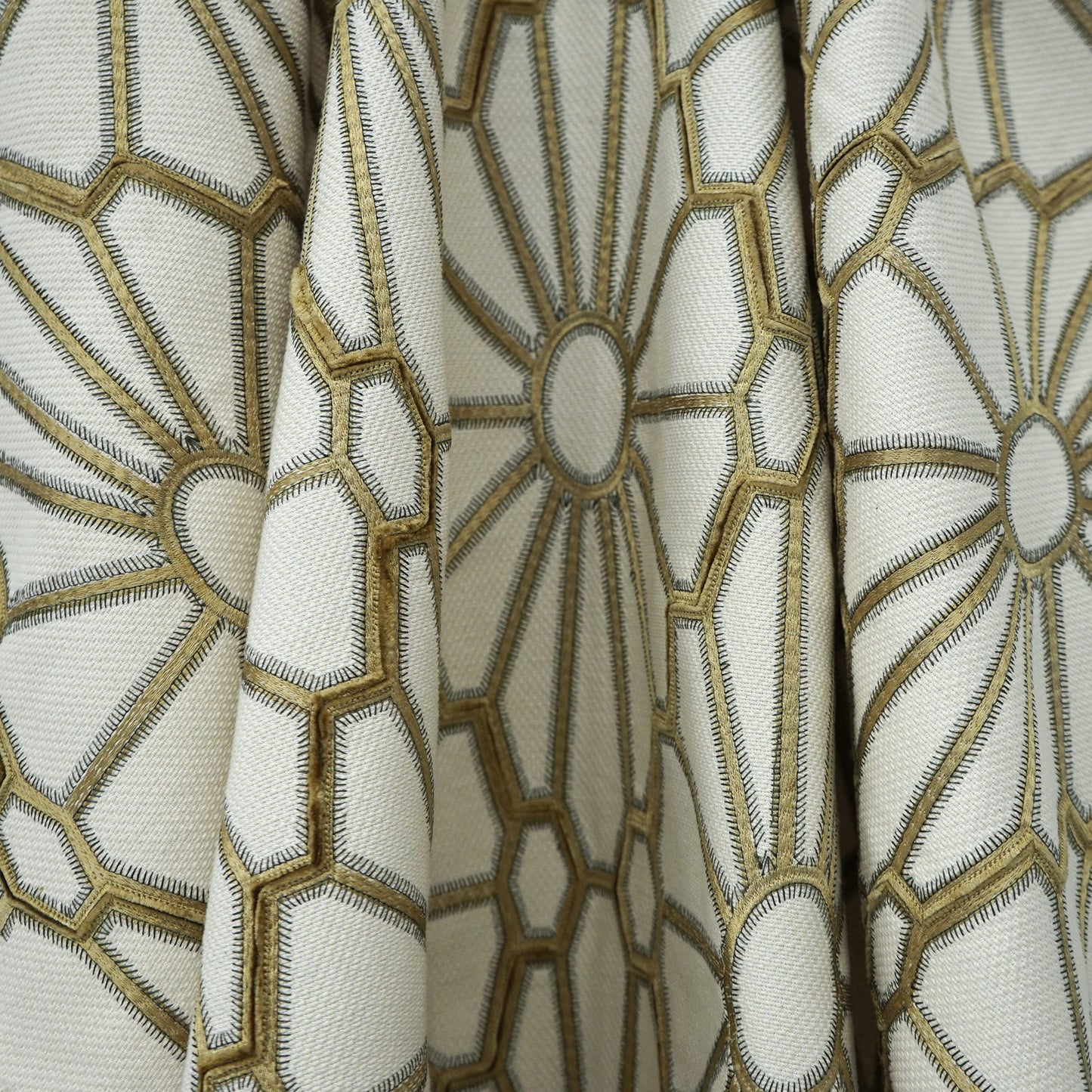 Cream drapery fabric with metallic gold embroidered geometric hexagon and circular motifs.