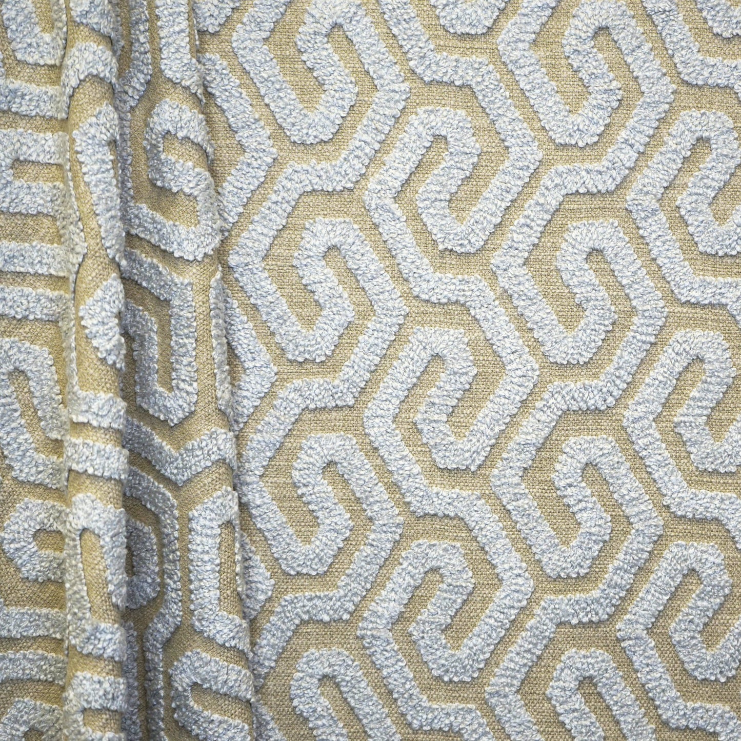 Beige upholstery fabric with white textured geometric maze pattern and raised boucle texture.