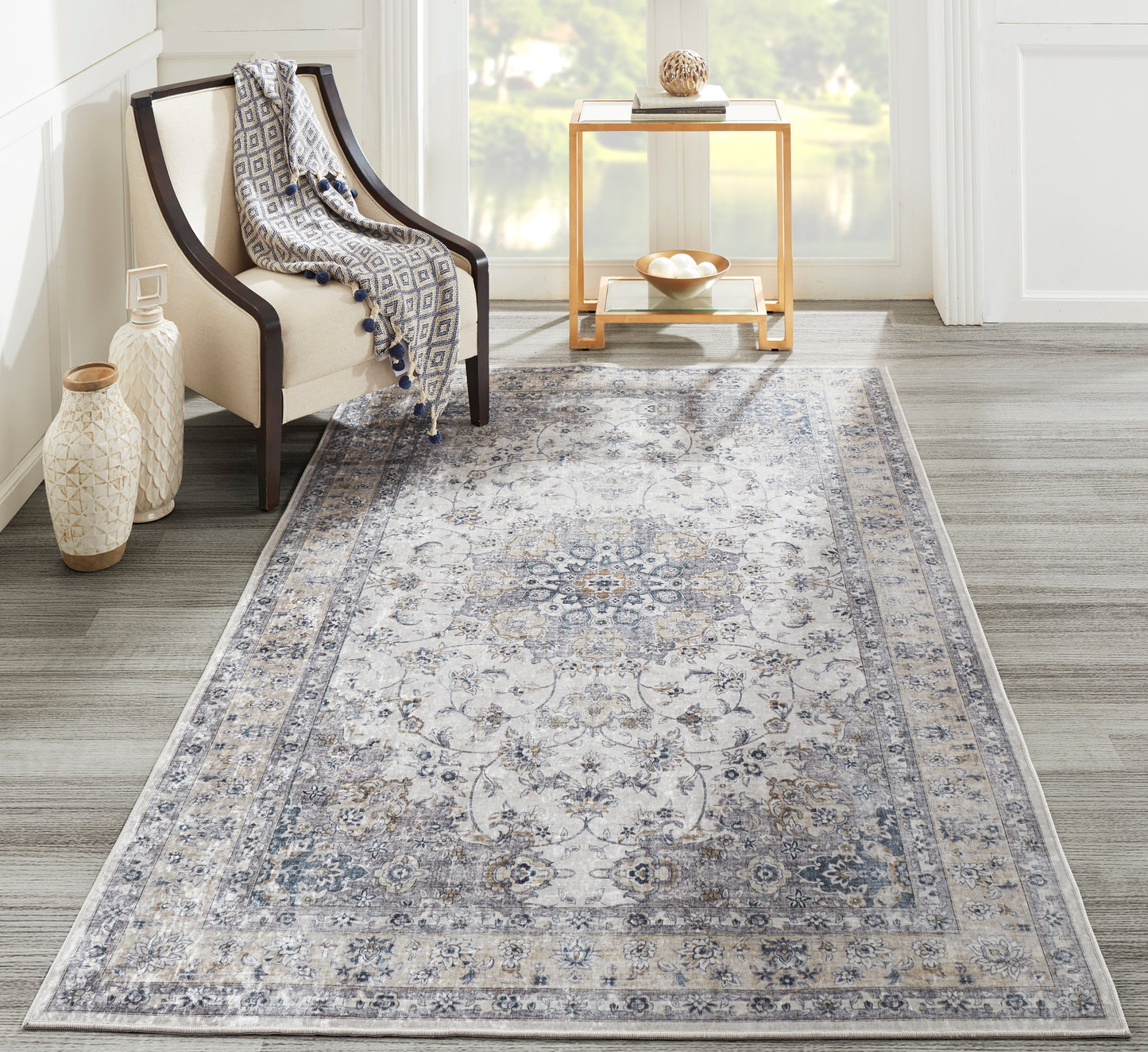 Rectangular gray Persian-style area rug with ivory and blue accents in a modern living room beside a beige chair.