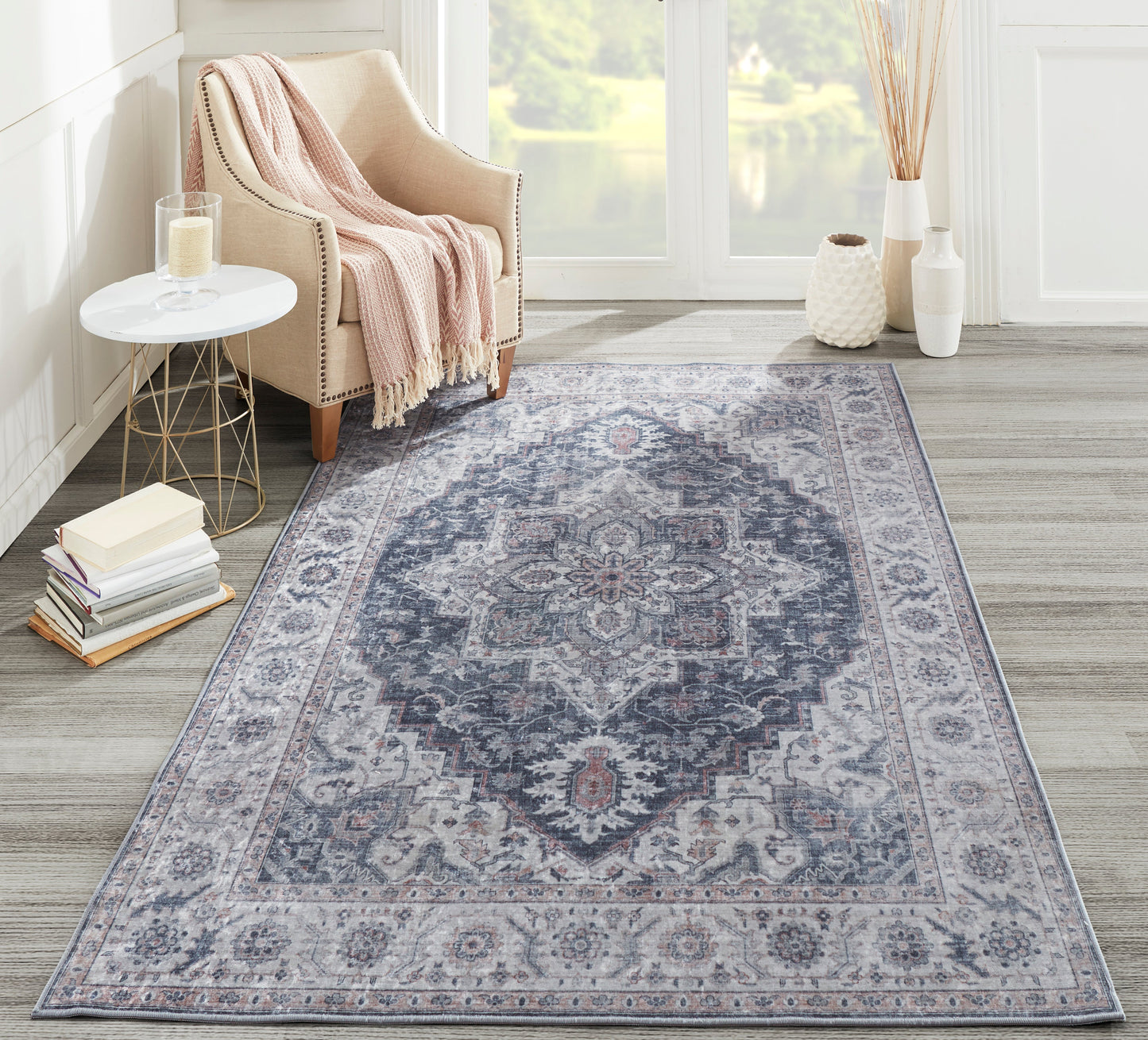 Gray oriental area rug with blue and ivory medallion pattern, in a bright living room beside a beige armchair.