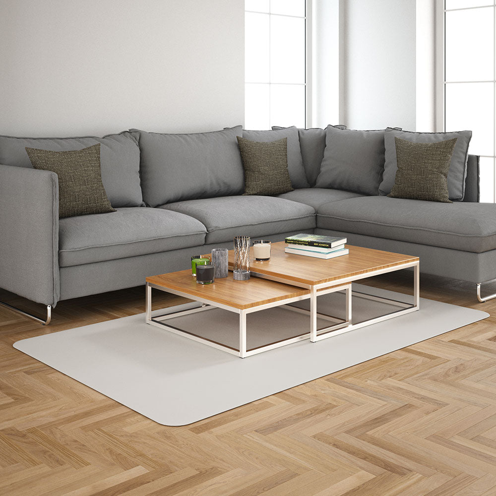 Modern gray sectional sofa with brown pillows, and light-wood nesting coffee tables with white metal frames on a pale rug.