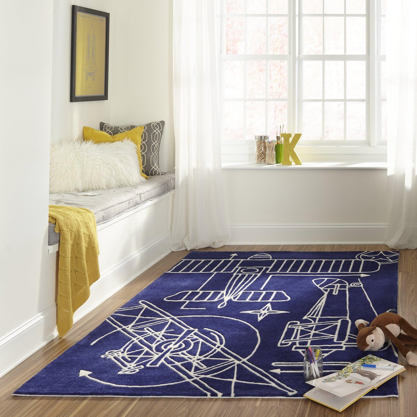 Navy blueprint rug by window-seat with fluffy pillow, yellow throw and geometric cushions.