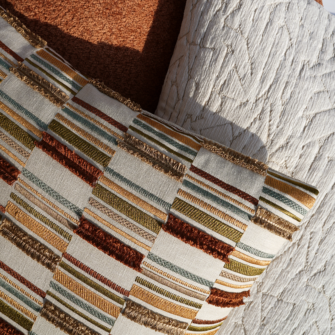 Woven striped pillow in beige, khaki, rust, and gold with fringed edges; boho chic texture, ideal for sofa or bed.