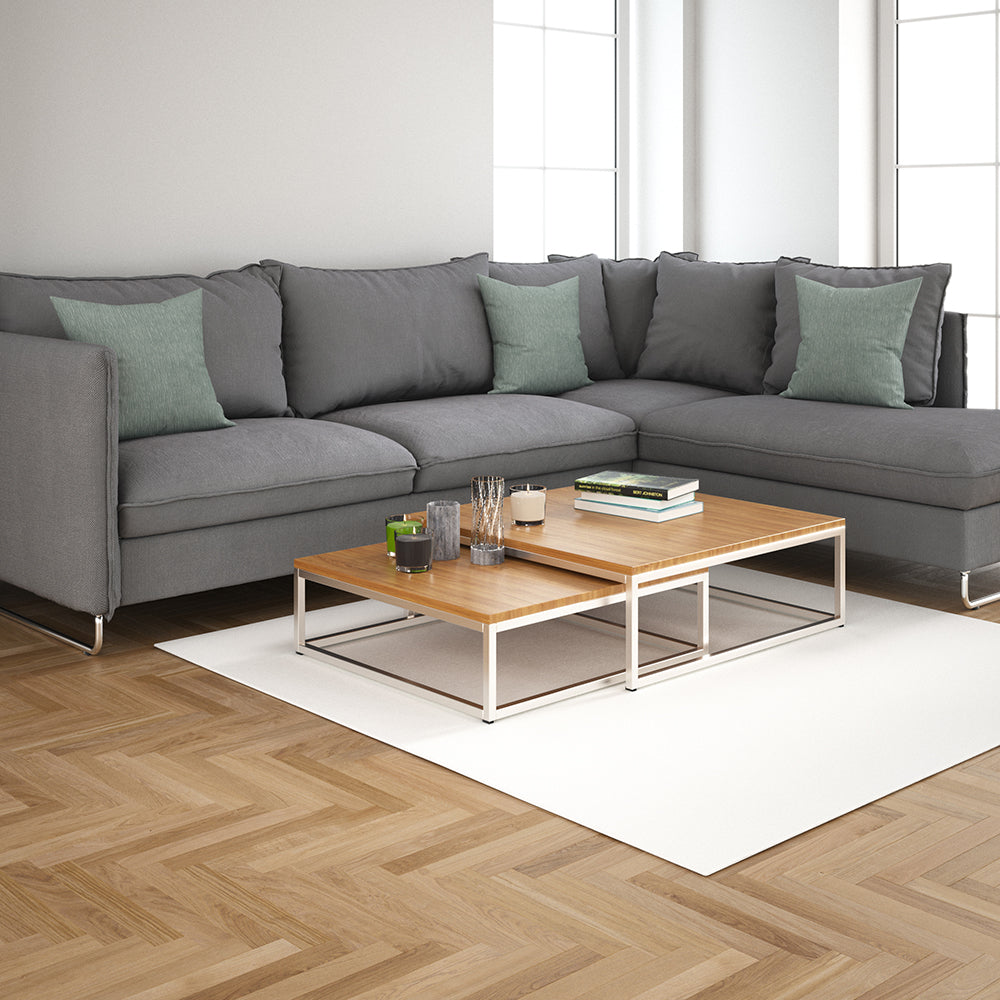 Modern gray sectional with green cushions and two-tier wooden coffee tables on a light rug in a sunlit living room.