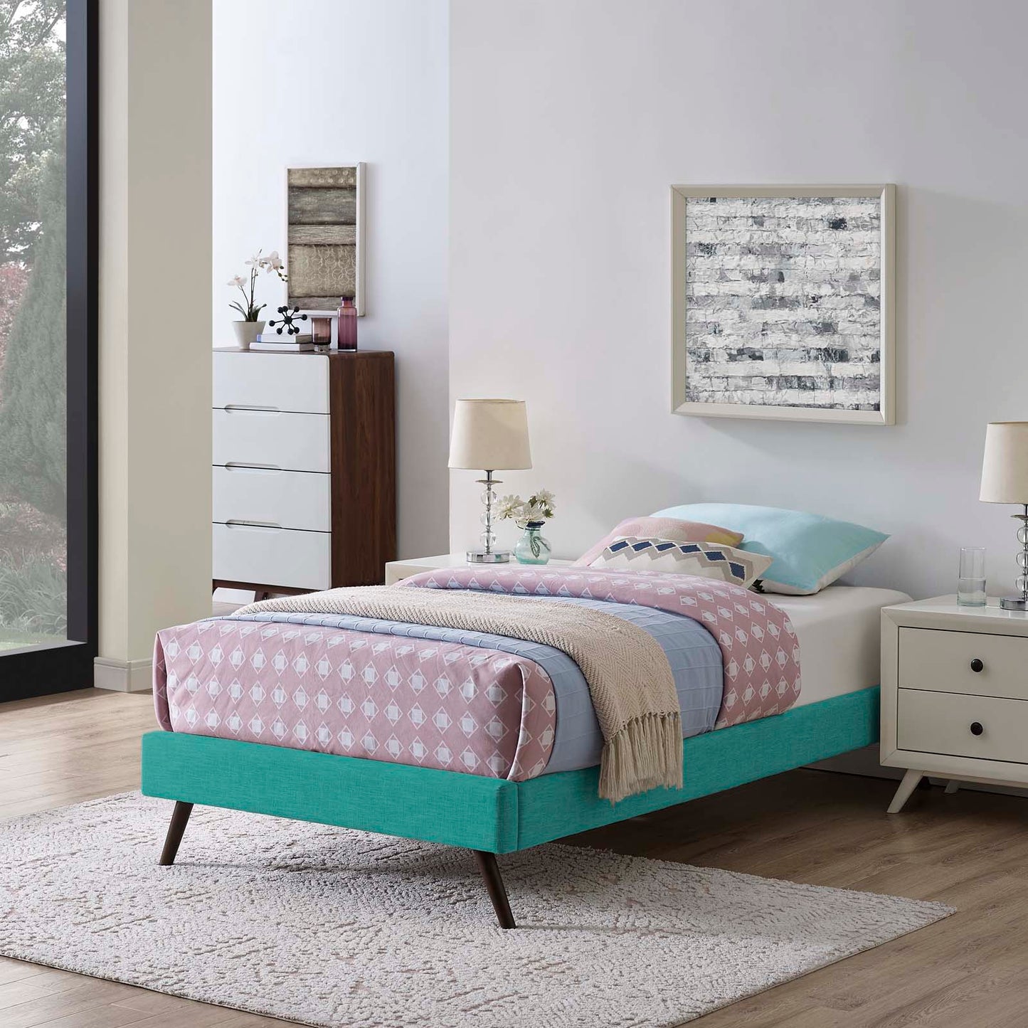 Teal fabric twin bed frame with round splayed legs, pink diamond quilt, light blue sheets, beige throw, white nightstands.