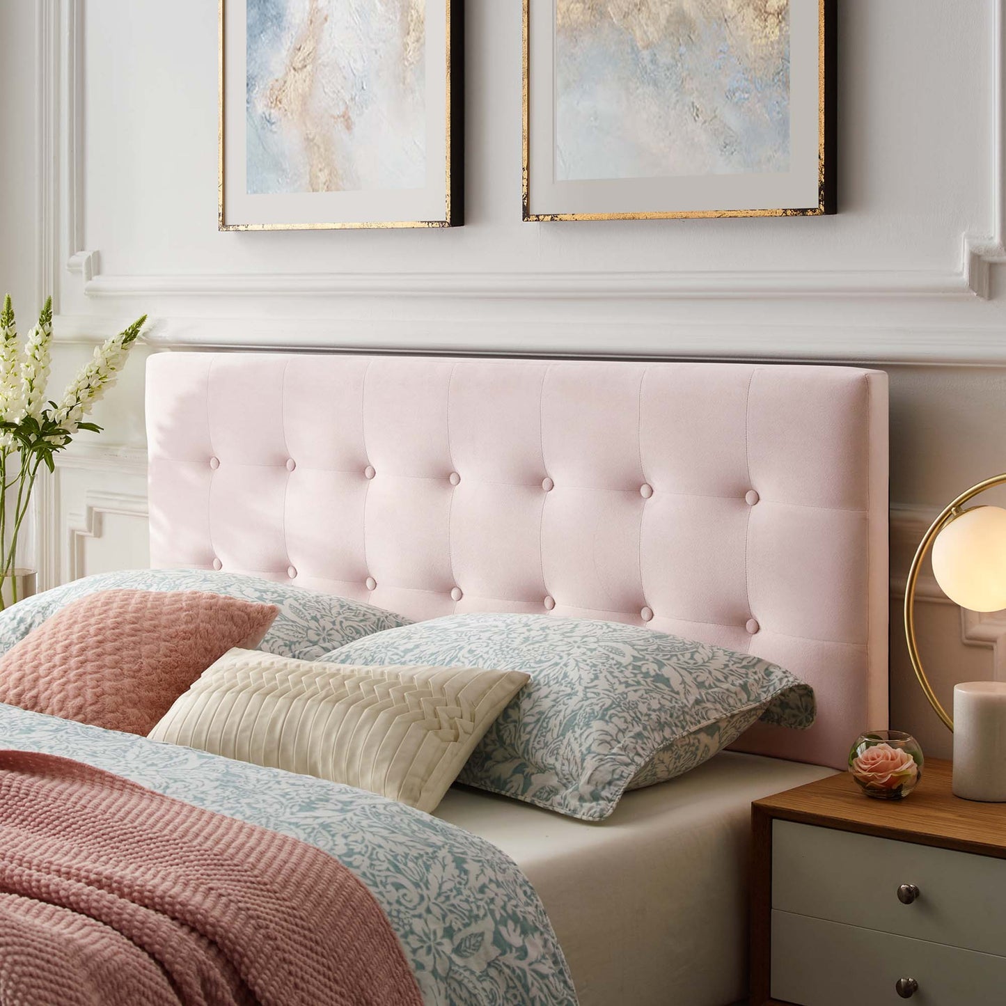 Soft pink tufted queen headboard with pastel damask bedding, beige and blue cushions, and a peach throw.