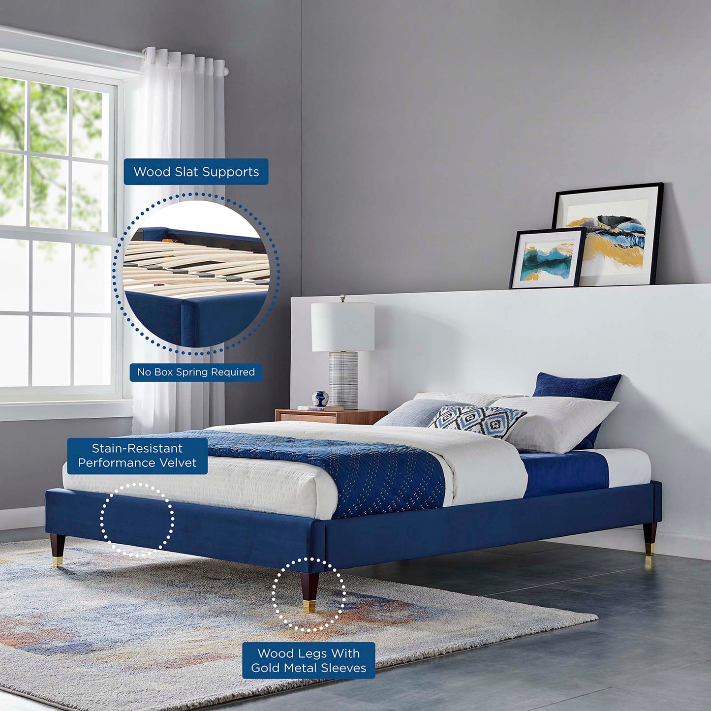 Navy velvet platform bed with wood slat supports, wood legs with gold sleeves, white bedding; stain-resistant fabric.