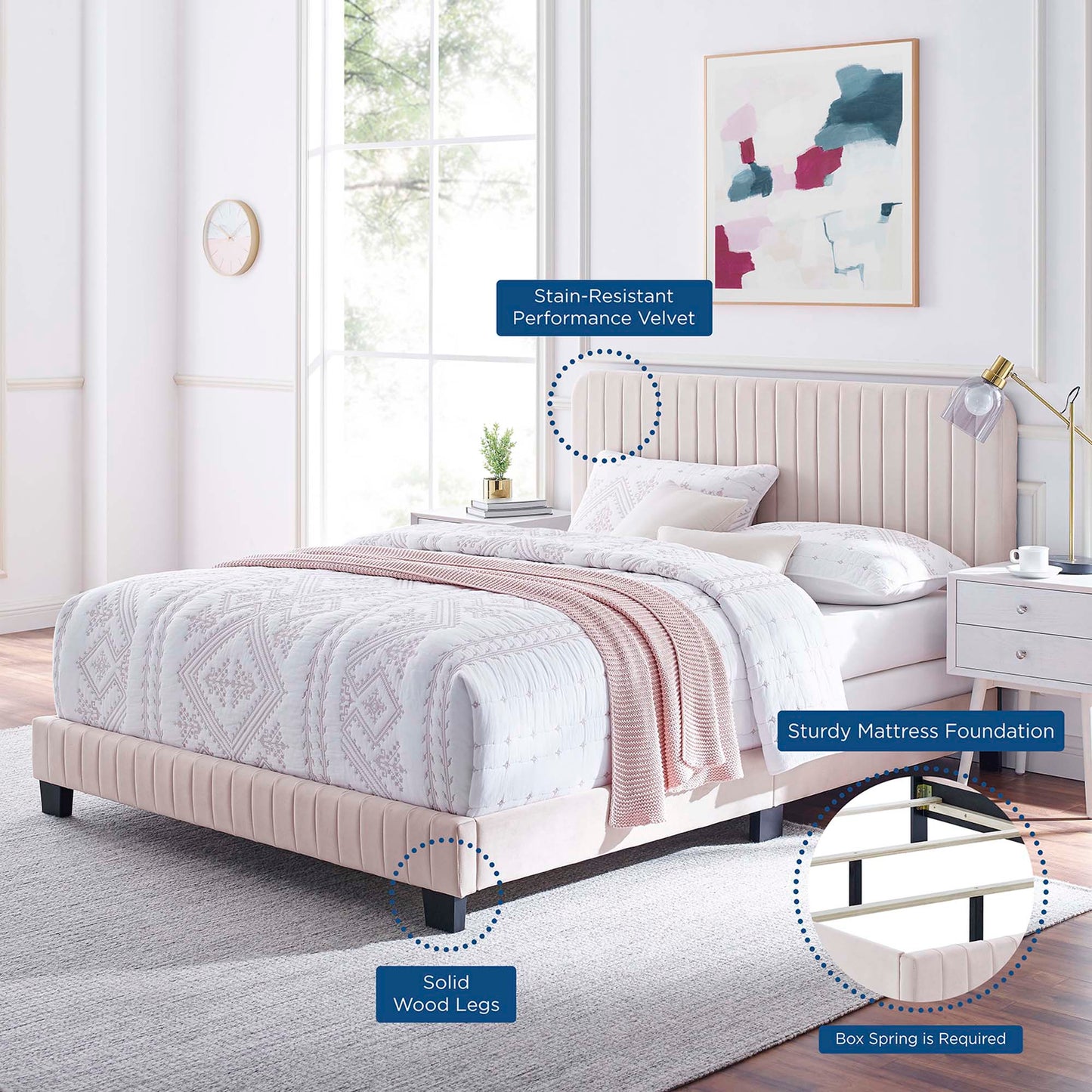 Soft pink velvet upholstered bed with tufted headboard and solid wood legs in a bright modern bedroom.