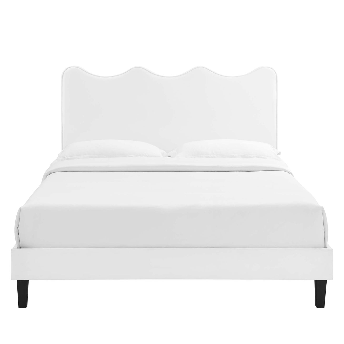 White upholstered bed with a scalloped headboard, platform frame and dark tapered legs; modern, minimal bedroom style.