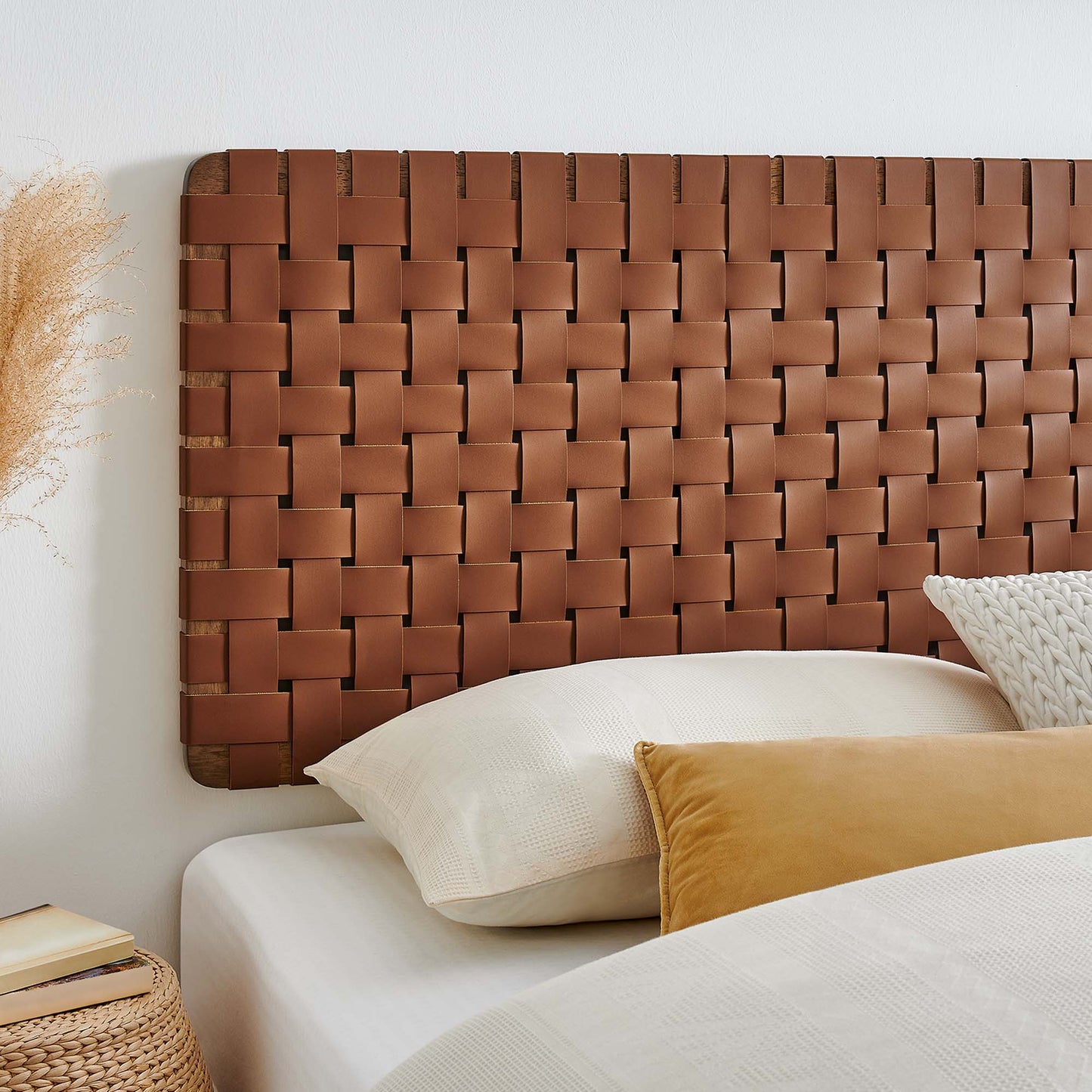 Walnut brown woven vegan leather headboard with white bedding & mustard pillow, pampas grass decor in a rustic modern bedroom.