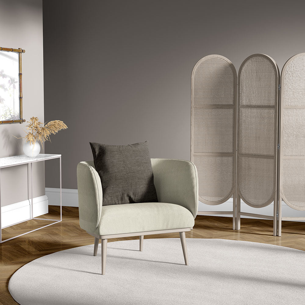 Cream solid fabric mid-century armchair with light-wood legs and a grey cushion in a modern living room.