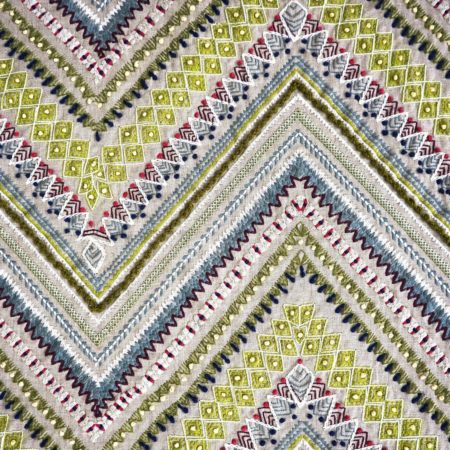 Colorful geometric woven fabric with chevron and diamond motifs in lime, blue, gray, cream; boho style linen-textured fabric