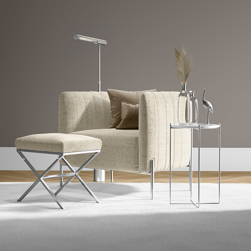 Beige solid fabric sofa with matching ottoman, chrome legs, and glass nesting tables with vases in a contemporary living room.