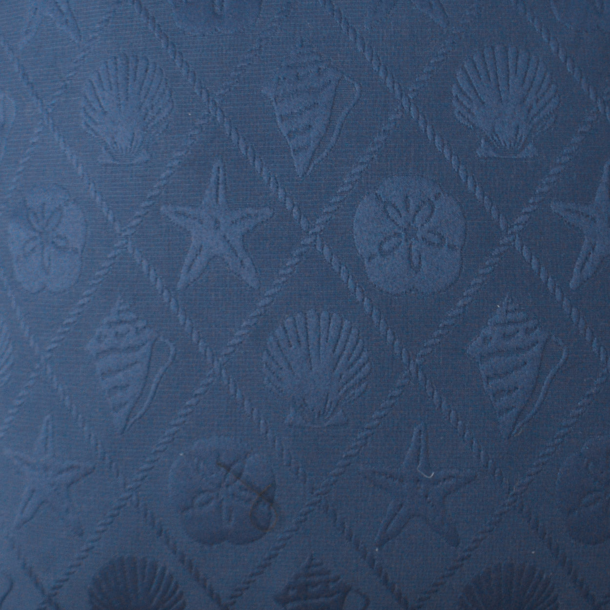 Blue outdoor lumbar pillow with a shell trellis pattern; quilted fabric with embossed starfish and shells in a diamond grid.