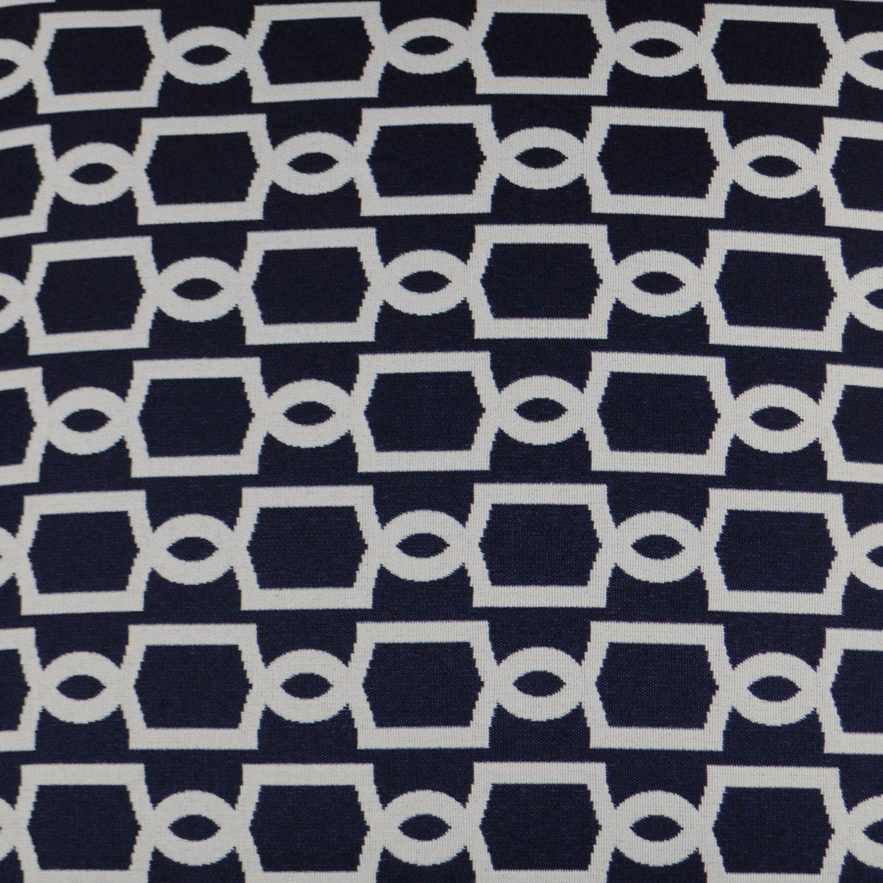 Navy trellis pattern on an outdoor lumbar pillow; white geometric trellis on navy fabric.