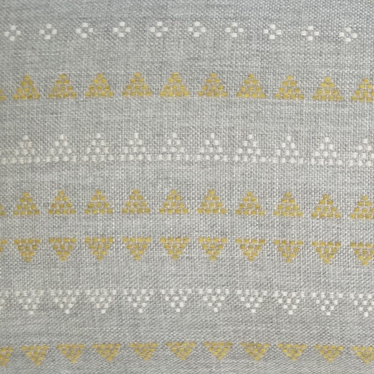 Grey woven fabric on an outdoor lumbar pillow featuring horizontal bands of white floral dots and yellow triangle motifs; geometric.